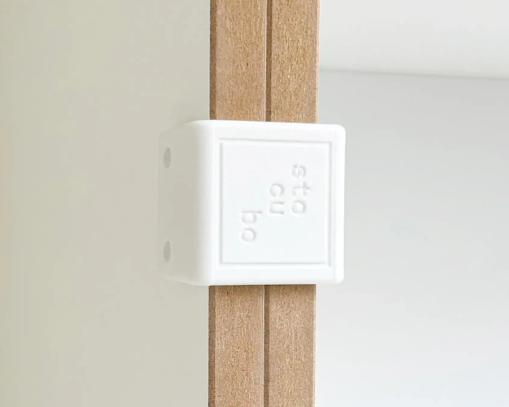 stocubo weiße Kunststoffklammer Close-up of a white plastic clip with a stocubo logo, securely connecting MDF shelving modules.